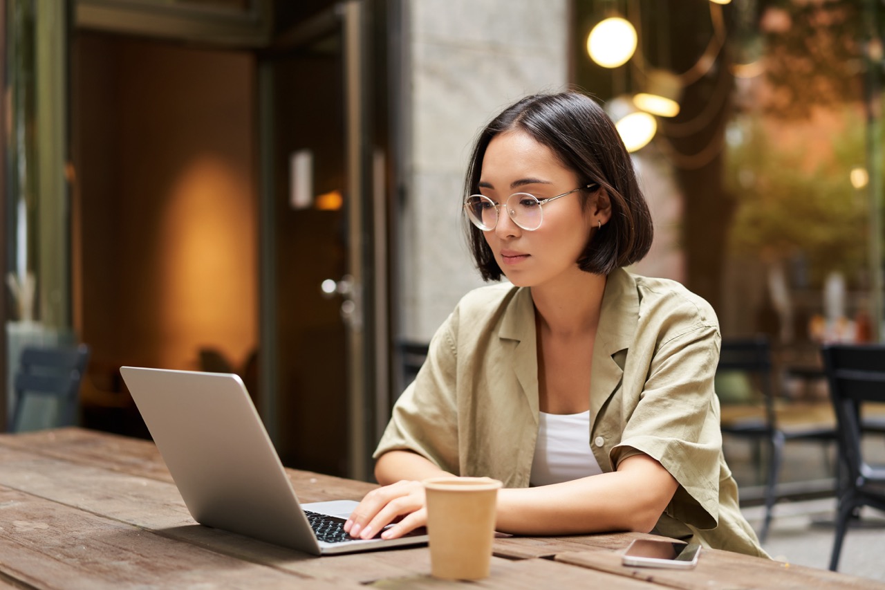young-woman-working-cafe-using-laptop-drinking-coffee-asian-girl-student-with-computer-stud lớn.jpeg