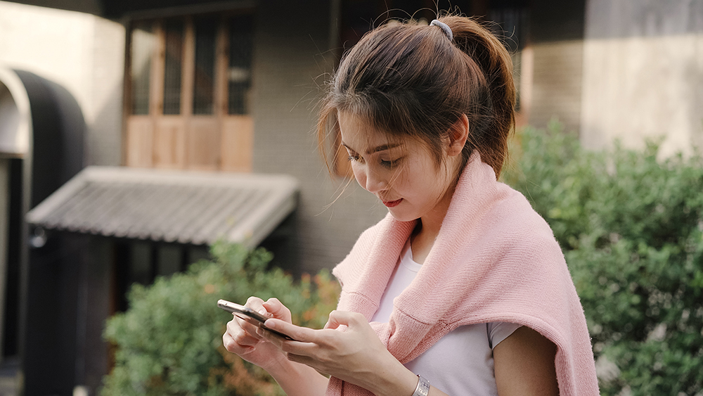 cheerful_asian_backpacker_blogger_woman_using_smartphone_direction.jpg